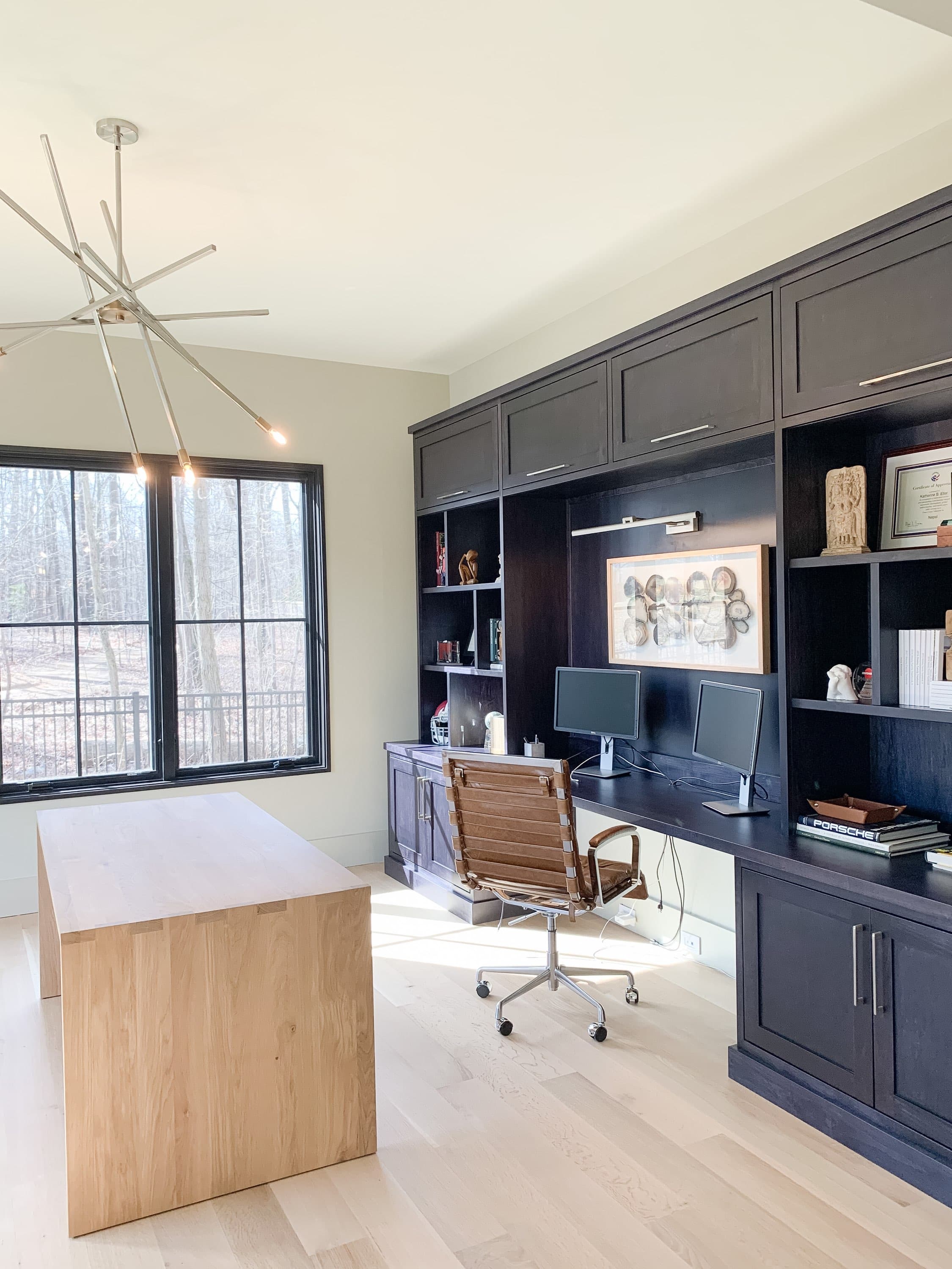 Dark floor-to-ceiling home office cabinetry with open shelves and a built-in desk