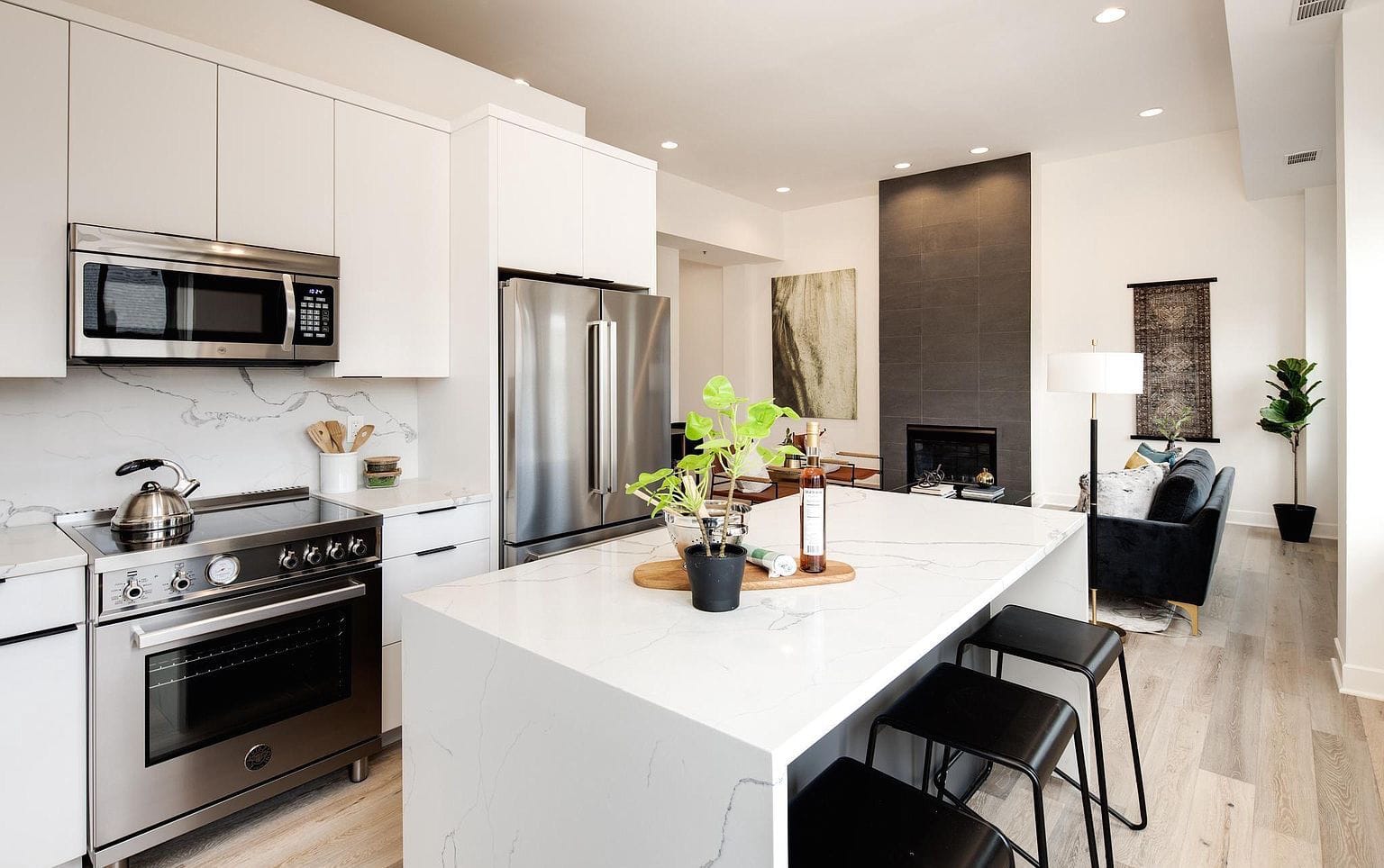 Modern white flat-panel kitchen with stainless appliances and a waterfall stone island