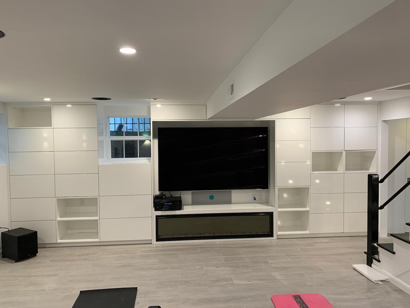 Gloss white built-in media wall surrounding a television and linear fireplace