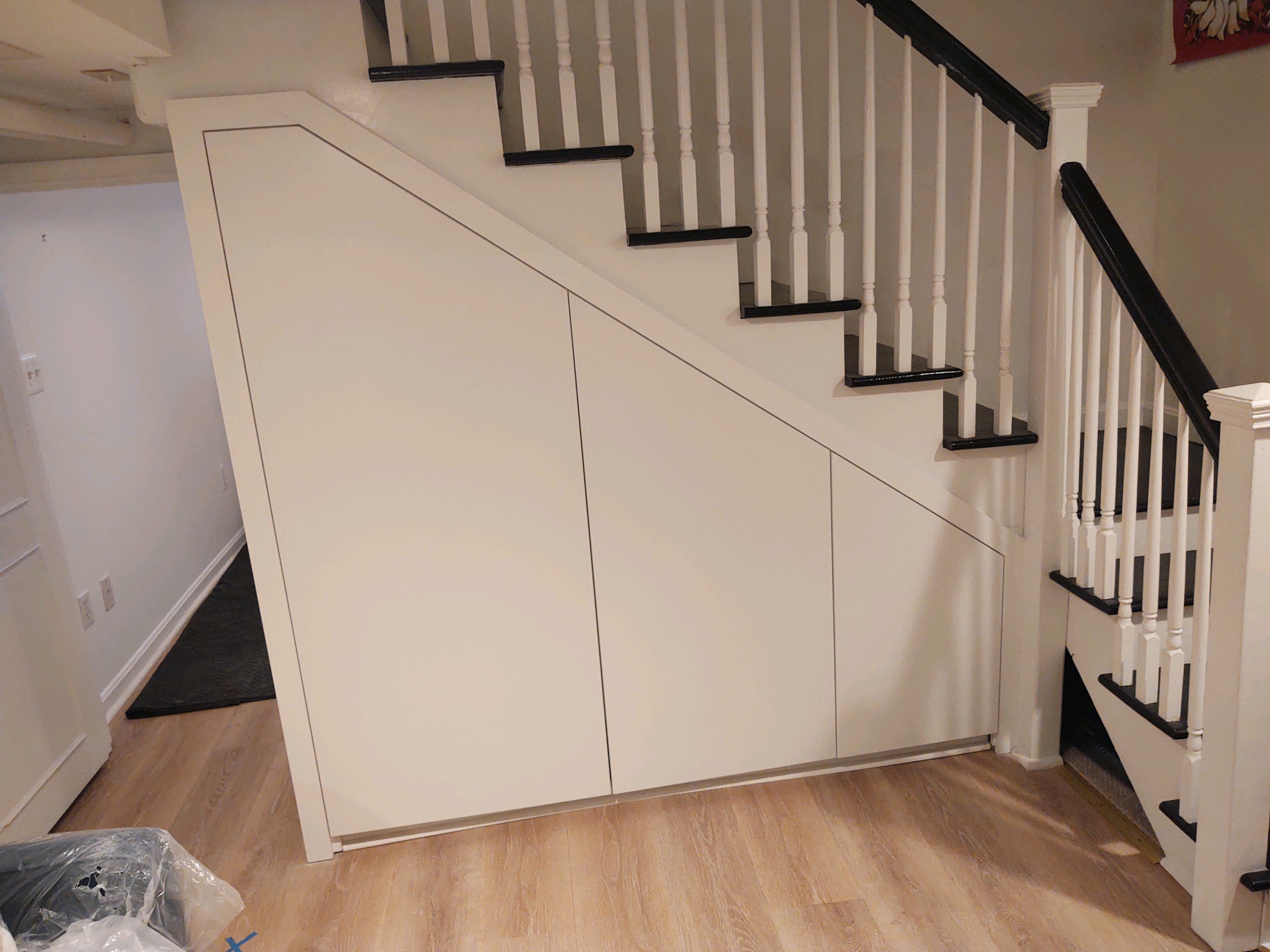 Flush white custom storage cabinets fitted beneath a staircase