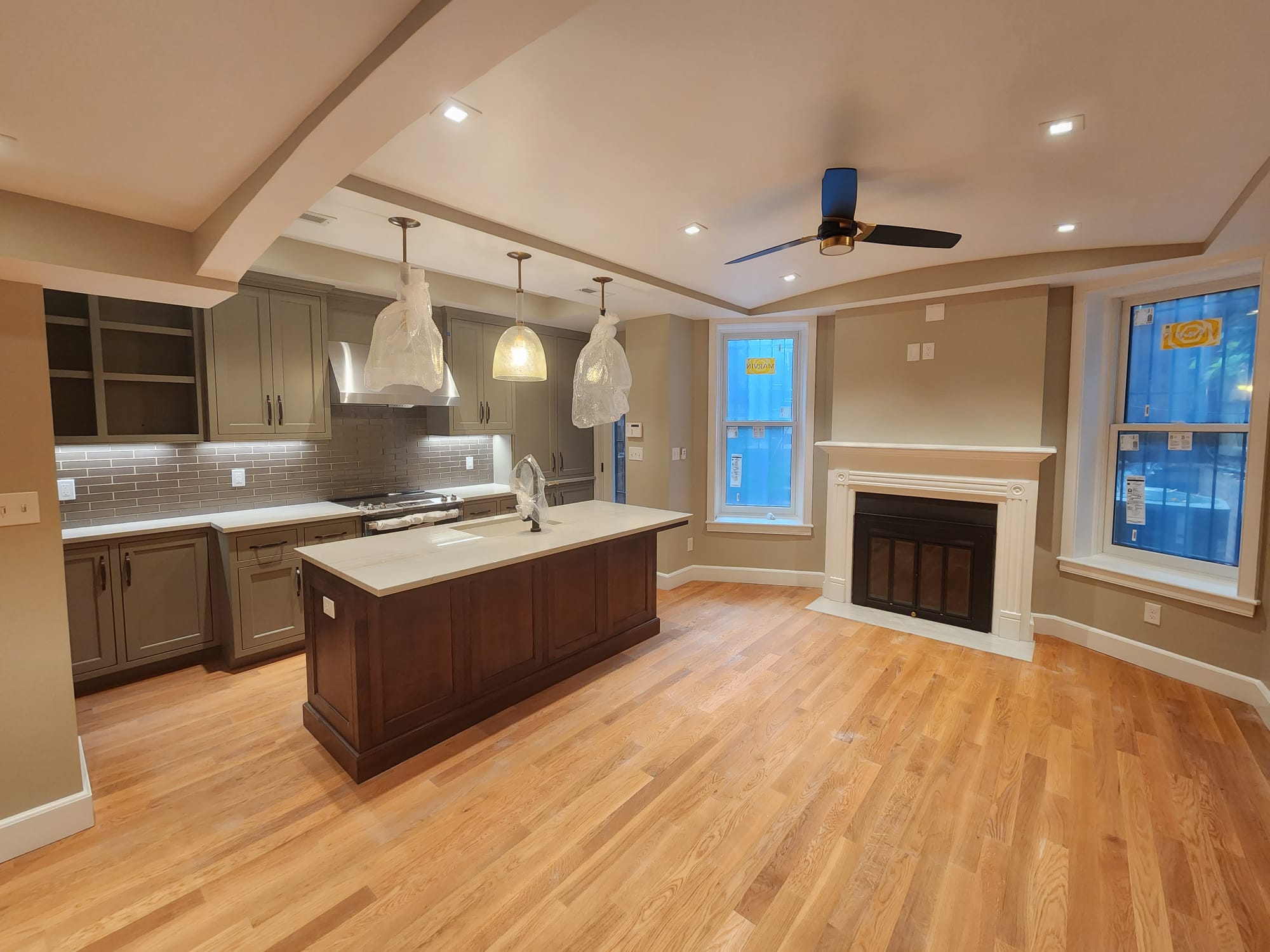 Traditional two-tone kitchen with gray perimeter cabinets and a dark wood island beside a fireplace