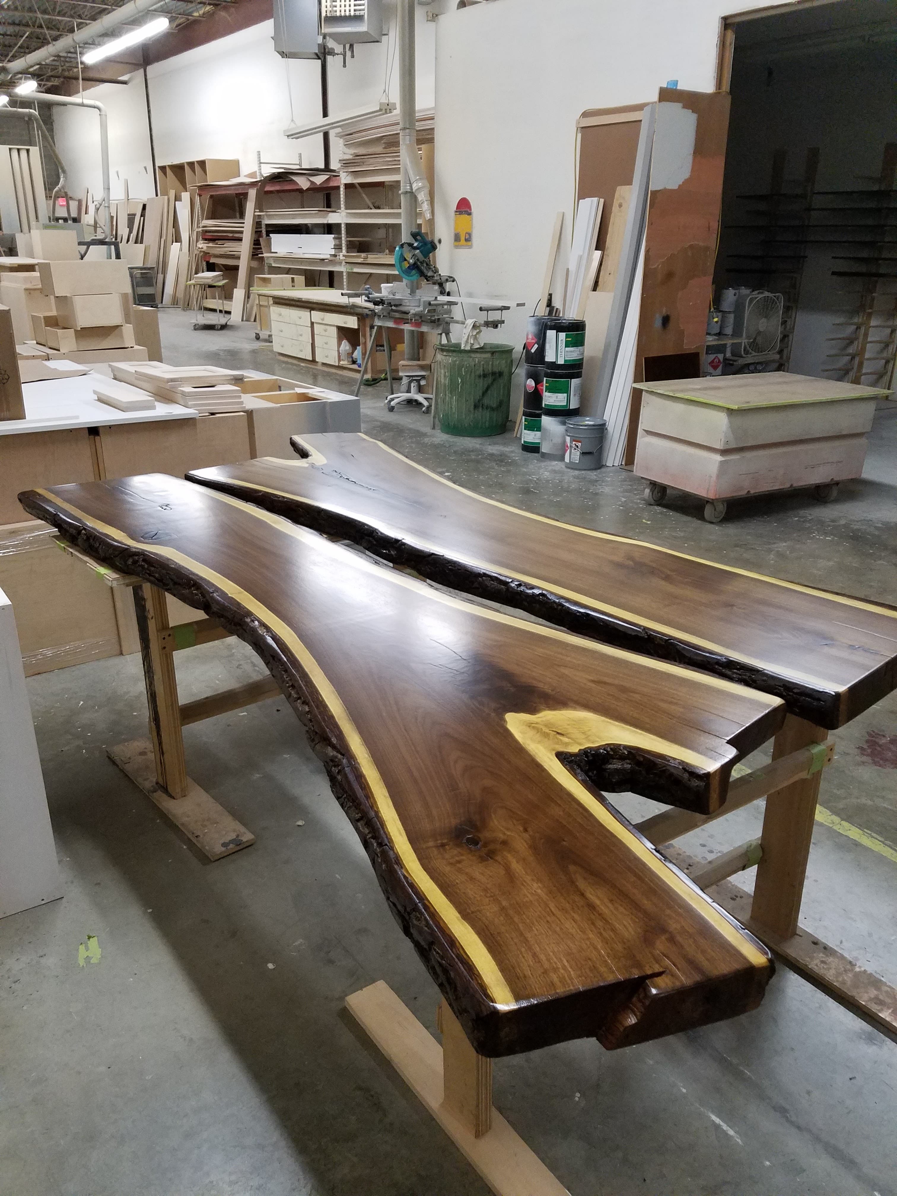 Finished live-edge wood slabs with dark natural edges and polished surfaces in the shop