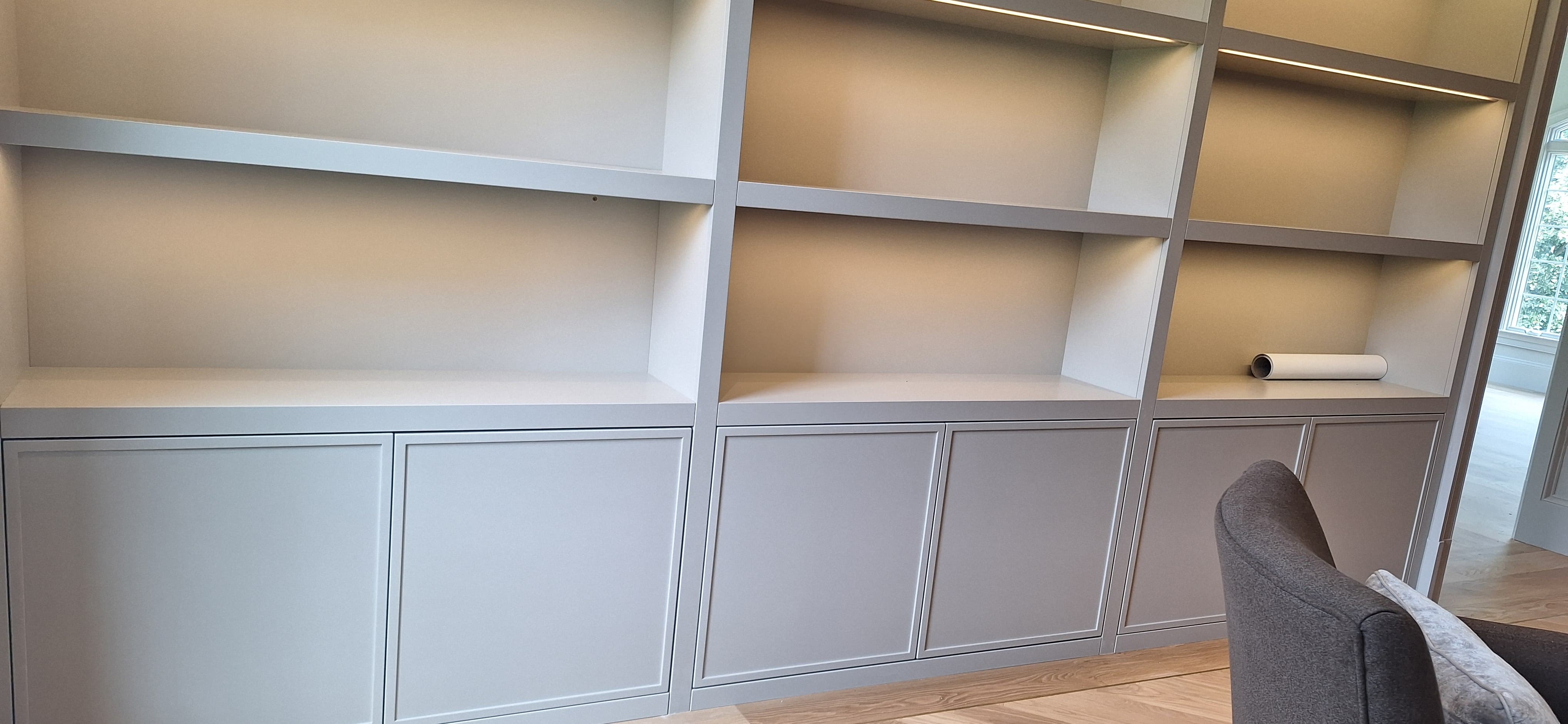 Closer view of light gray built-in shelving and lower cabinet doors with integrated shelf lighting
