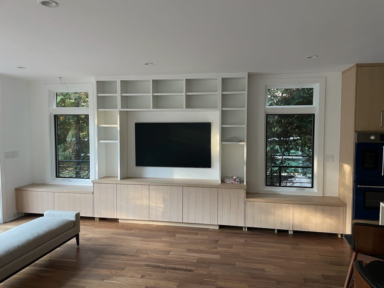 Custom TV wall with white open shelving and light wood built-in cabinets